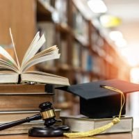 Law education, legal educational study, school for lawyer, legistration, litigation, judicial knowledge learning concept with court judge gavel and textbook with mortarboard on books in library